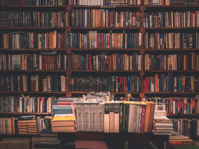 Bookshelves crammed full of books, with more books stacked up on tables