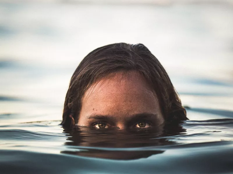 A woman is submerged in water that comes up to just below her open eyes