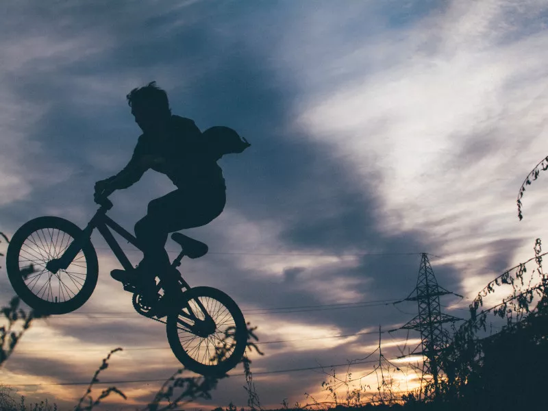 A silhouette of a person jumping in midair while riding a bicycle